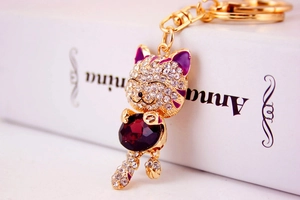 Close-up of golden lucky cat keychain with purple crystal and sparkling rhinestones
