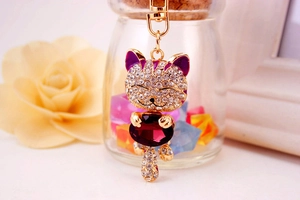 Detail of a lucky cat keychain with purple crystal and sparkling rhinestones