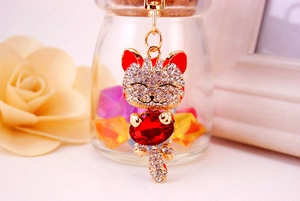 Close-up of golden lucky cat keychain with sparkling white rhinestones and a red gem