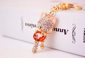 Close-up of golden lucky cat keychain with orange crystal gem and sparkling rhinestones