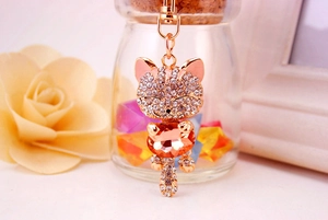 Macro view of crystal lucky cat keychain with orange gemstone and rose gold plating
