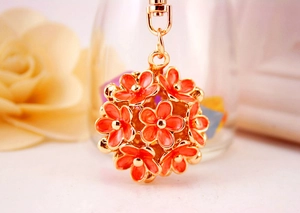 Macro shot of orange enamel flower ball keychain with gold-plated lobster clasp