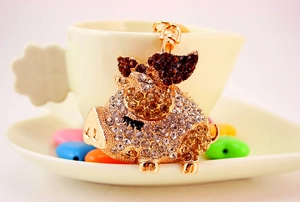 Close-up of a winged pig keychain featuring sparkling crystals on a gold metal base