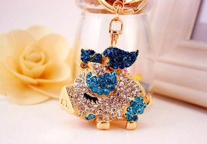 Macro shot of a golden pig keychain featuring sparkling blue and clear rhinestones