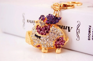 Detailed close-up of a sparkling gold pig keychain encrusted with purple and clear rhinestones