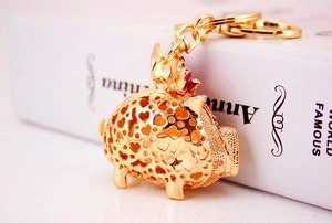 Close-up of golden flying pig keychain with heart cut-outs and red rhinestone accents