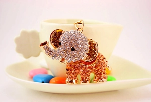 Close-up of diamond-studded elephant keychain hanging on a white ceramic heart cup
