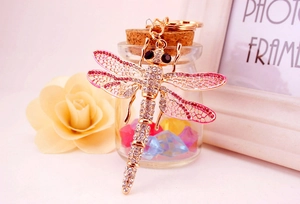 Macro shot of a golden metal dragonfly keychain with sparkling pink and clear rhinestones