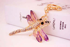 Detail of dragonfly keychain with purple enamel wings and sparkling rhinestones on gold metal