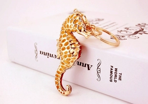 Detailed view of seahorse keychain with gold openwork, red enamel and sparkling rhinestones