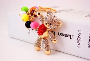Close-up of rhinestone teddy bear keychain with colorful beads on a book surface