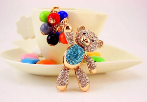 Detail of a golden bear keychain featuring blue crystals and colorful beaded accents