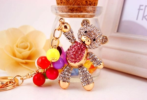 Detail of a gold teddy bear keychain with sparkling pink and clear rhinestones