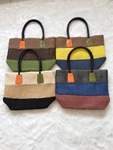 Flat lay of four handmade woven straw tote bags in various striped color combinations