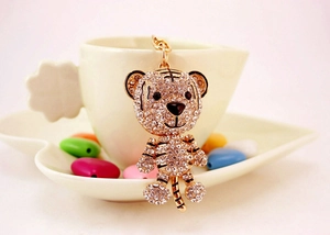 Detail of a golden tiger keychain with white rhinestones hanging on a ceramic cup