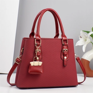 Detailed texture of burgundy tote bag with gold hardware and stylish small bag charm