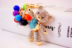 Detailed close-up of a gold metal teddy bear keychain with sparkling blue rhinestones