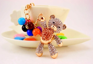 Detail of a gold rhinestone teddy bear keychain with colorful beads for handbags