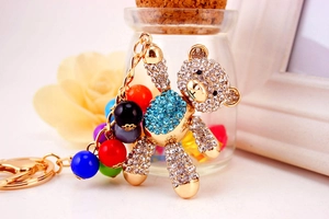 Detail of a golden bear keychain with blue rhinestones and colorful acrylic beads