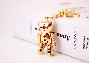 Detailed view of a golden teddy bear keychain with heart cutouts and sparkling rhinestones