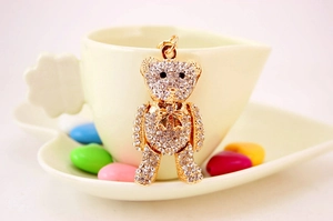 Detail of a gold-plated teddy bear keychain with sparkling rhinestones and a bow tie
