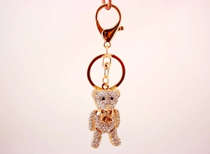 Close-up of cute golden bear keychain with sparkling white rhinestones and a bow detail