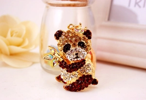 Dettaglio di un portachiavi a forma di panda dorato con strass colorati e una corona
