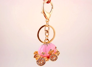 Close-up of pink enamel pumpkin carriage keychain with sparkling rhinestones and gold alloy finish