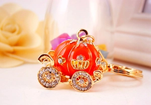 Detail view of pumpkin carriage keychain with orange enamel and gold-tone finish
