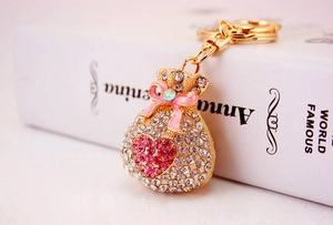 Detailed shot of a gold alloy money bag keychain with pink bow and inlaid rhinestones