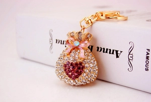 Detail of a sparkling gold lucky bag keychain with rhinestones and pink bow detail