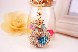 Detailed close-up of a golden alloy lucky bag keychain with crystals and blue bow decoration