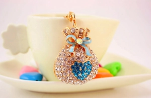 Detail of sparkling lucky bag keychain with blue heart rhinestones and bow on a cup