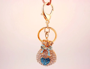 Detail of crystal lucky bag keychain with blue heart and ribbon on pink background