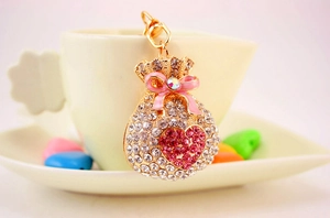 Detailed view of lucky bag keychain with pink crystals and heart pattern on a cup
