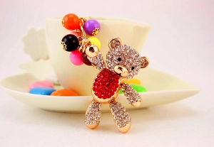Detailed view of a golden teddy bear keychain with red and clear rhinestones and beads
