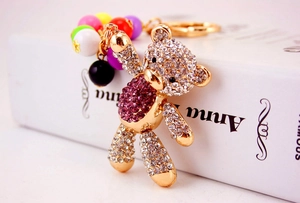 Detail of a sparkling rhinestone bear keychain with colorful beads on a white book