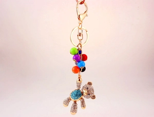 Close-up of golden bear keychain with colorful beads and sparkling blue rhinestones
