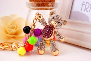Detailed close-up of a golden alloy bear keychain with sparkling purple rhinestones and beads