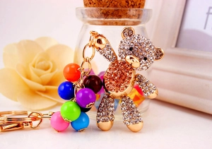 Detail of golden rhinestone bear keychain with colorful beads and metal clasp