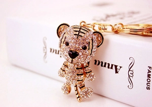 Detailed view of a gold tiger keychain with sparkling rhinestones on a white book