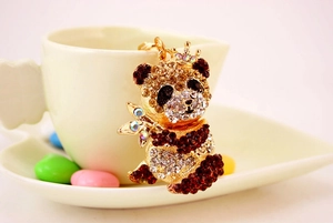 Dettaglio ravvicinato di un portachiavi a forma di panda dorato con strass marroni e chiari
