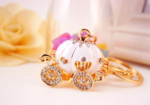 Close-up of a gold pumpkin carriage keychain with white enamel and sparkling rhinestones