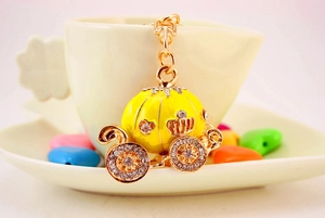 Detail of yellow enamel pumpkin carriage keychain with rhinestones on a cup edge