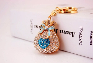 Macro view of gold lucky money bag keychain with sparkling crystals and blue heart detail