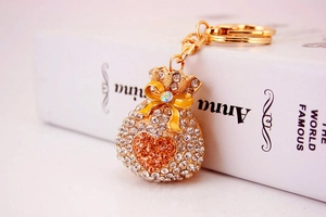 Macro detail of golden money bag keychain with rhinestones and yellow enamel bow
