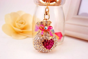 Close-up of golden lucky bag keychain with white rhinestones and pink enamel bow