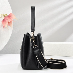 Detail of black lychee texture bucket bag with gold hardware and wide shoulder strap