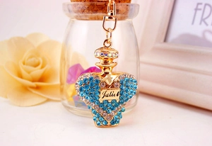 Close-up of golden perfume bottle keychain with blue rhinestones and Julie engraving