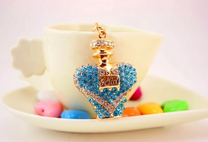 Detail of crystal perfume bottle keychain in gold with blue rhinestones and soft background
